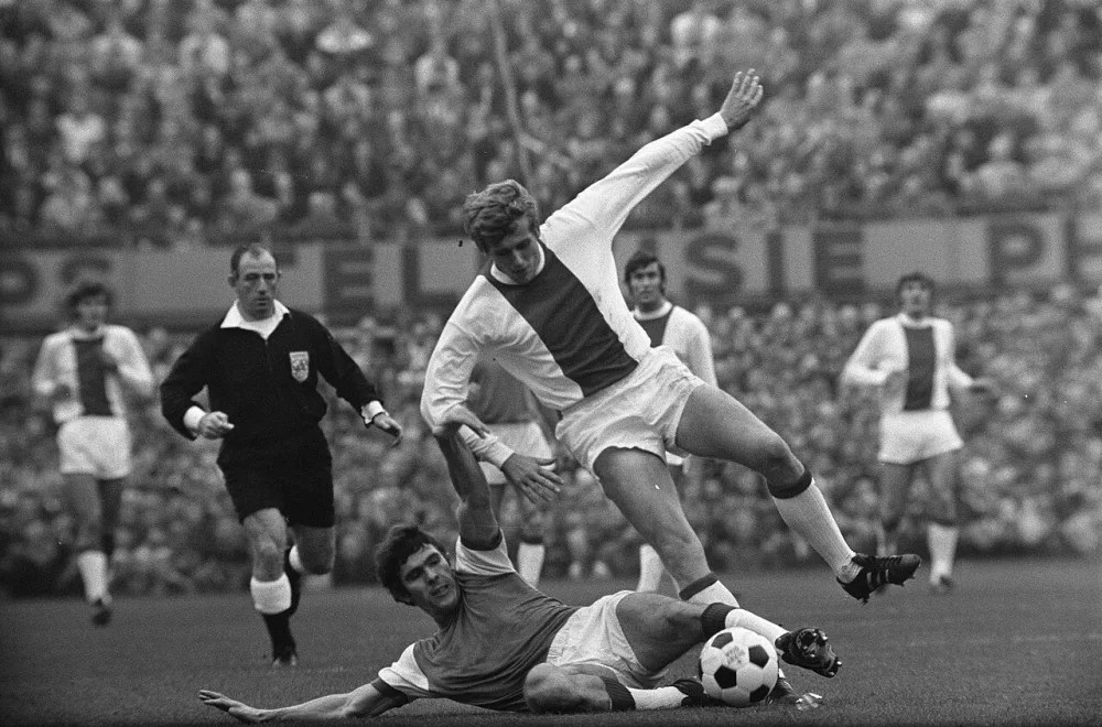 Feyenoord tegen Ajax 1-0. Van Hanegem haalt bal weg voor voeten van Piet Keizer , links scheidsrechter Dorpmans. Foto: Eric Koch / Anefo, Nationaal Archief (CC0).