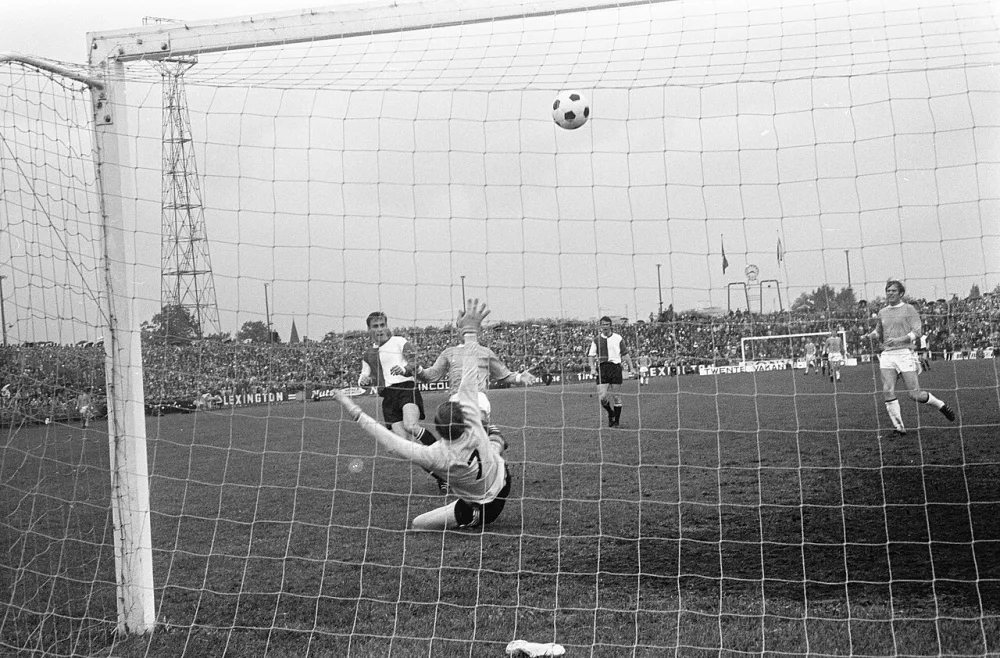 Twente tegen Feijenoord 0-1. Feijenoord kampioen van Nederland in Eredivisie, Ove Kindvall (links) heeft goal gescoord, keeper Schrijvers is kansloos. Foto: Eric Koch / Anefo, Nationaal Archief (CC0).