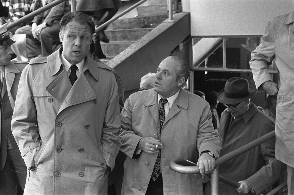Feyenoord tegen AZ*67 2-1, Barcelona trainer Michels op tribune, in gesprek met Feyenoord manager Guus Brox. Foto: Bert Verhoeff / Anefo, Nationaal Archief (CC0).