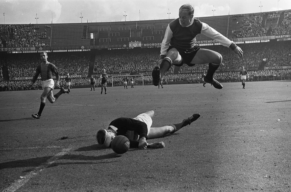 Feyenoord tegen ADO 2-1, keeper Ton Thie (ADO) werpt zich op de bal, Gerard 'Pummie' Bergholtz weet te ontwijken. Foto: Eric Koch / Anefo, Nationaal Archief (CC0).