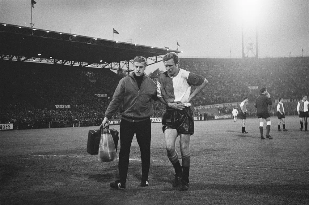 Ajax tegen Feyenoord 2-0, nummer 12 Hans Kraay geblesseerd nummer 13, 14 en 15 spelmomenten. Foto: Joost Evers / Anefo, Nationaal Archief (CC0).