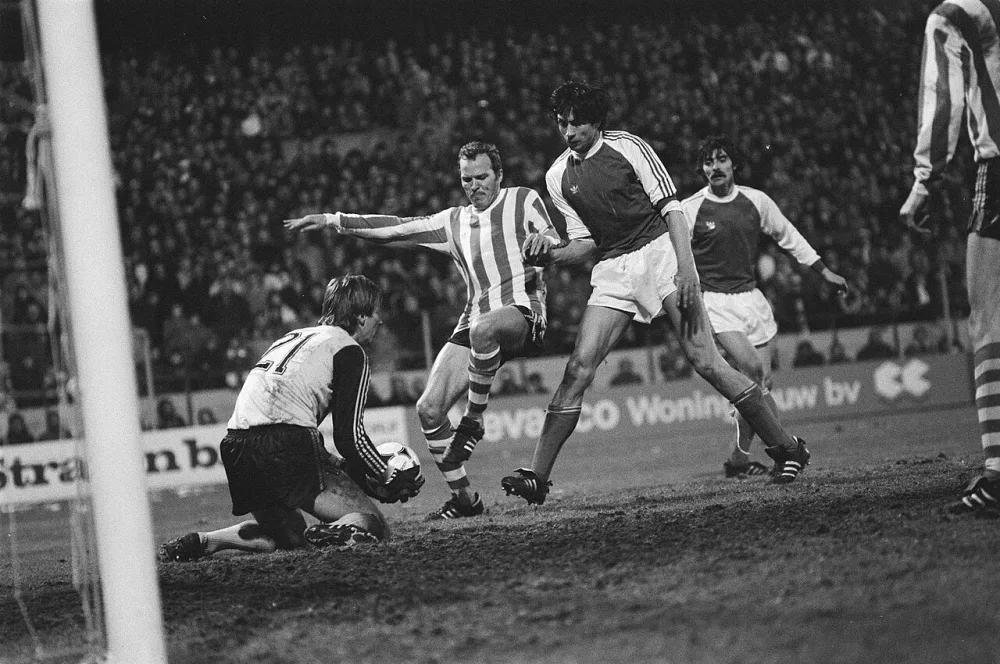 PSV tegen Feyenoord 1-2. Willy van der Kerkhof in duel met keeper Van Engelen (l.) en Stanley Brard. Foto: Hans van Dijk / Anefo, Nationaal Archief (CC0).