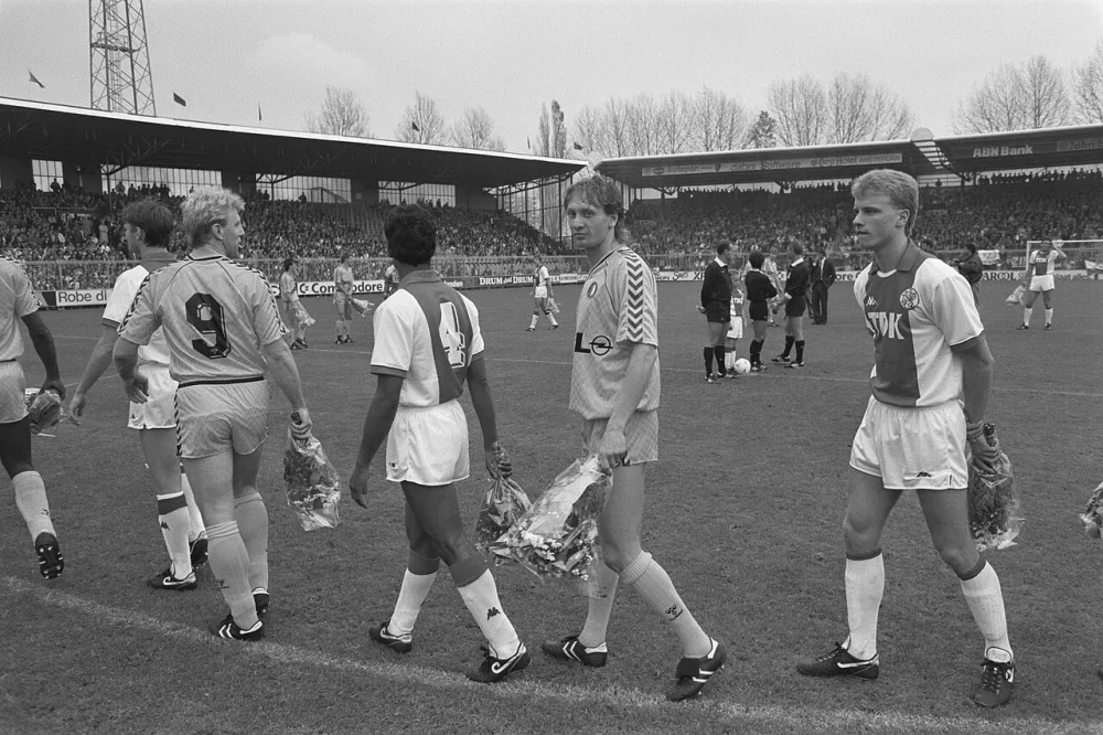 Ajax tegen Feyenoord; spelers met bloemen op het veld in kader actie tegen vandalisme. Foto: Bart Molendijk / Anefo, Nationaal Archief (CC0).