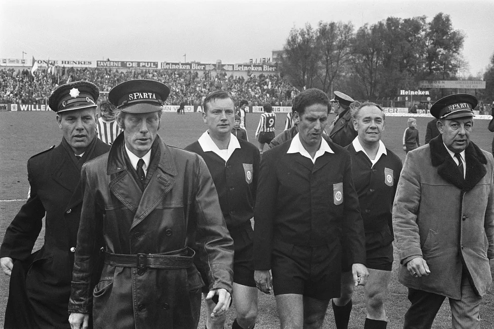 Scheidsrechter Van der Kroft verlaat onder politiebescherming het veld. Foto: fotograaf onbekend / Anefo, Nationaal Archief (CC0).
