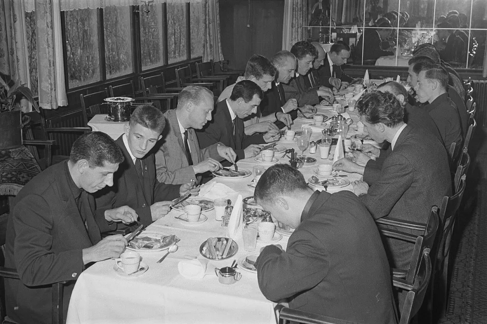 Feijenoord in Breda in trainingskamp, de spelers aan de maaltijd, linkerkant tafel Van der Gijp , Hordijk, Kruiver, Moulijn, Kraay, Fuchs, Kreijermaat, Buitendijk, ?. Aan de ander kant in het midden…. Foto: Eric Koch / Anefo, Nationaal Archief (CC0).