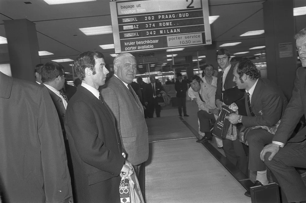 Elftal Feyenoord arriveert op Schiphol uit Milaan. Coen Moulijn bij de bagageband. Foto: Rob Mieremet / Anefo, Nationaal Archief (CC0).