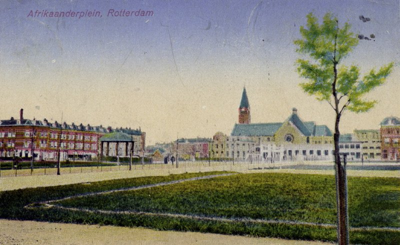 Het Afrikaanderplein rond 1930, na de volkstuintjes ingericht als plantsoen met muziektent. Op de achtergrond de Sint-Franciscuskerk. Ansichtkaart, Stadsarchief Rotterdam (CC0, via Wikimedia Commons)